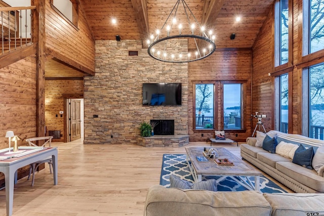 living area with a stone fireplace, wooden ceiling, wood finished floors, a notable chandelier, and high vaulted ceiling