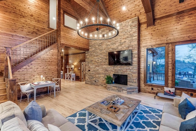 living room featuring wooden walls, beamed ceiling, stairs, a notable chandelier, and high vaulted ceiling