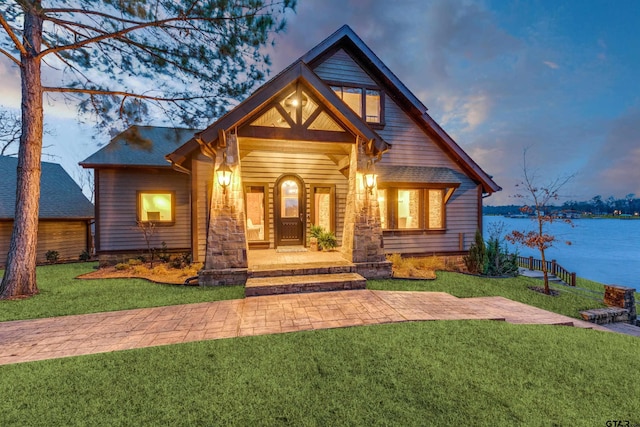 view of front of home featuring stone siding, a porch, and a front lawn