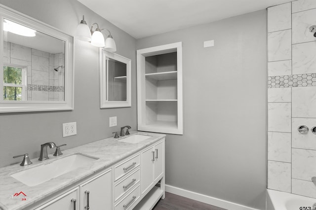 bathroom featuring wood-type flooring, vanity, and tiled shower / bath