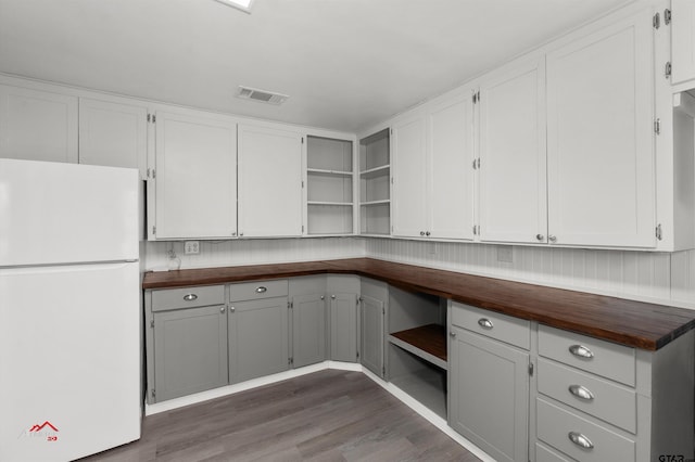 kitchen featuring white cabinets, butcher block counters, dark wood-type flooring, and white refrigerator