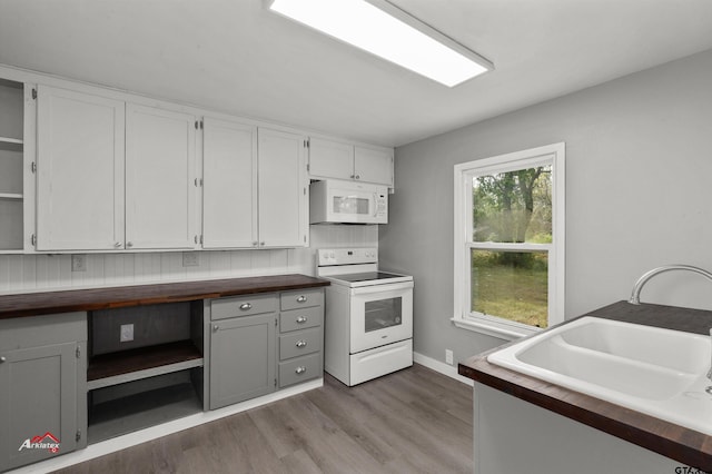 kitchen with butcher block counters, white appliances, hardwood / wood-style floors, and white cabinets