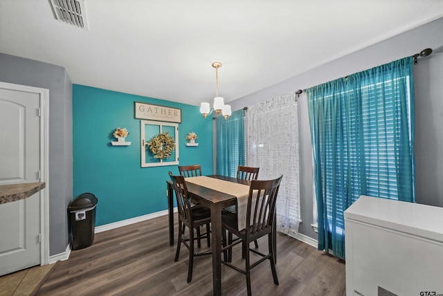 dining area with dark hardwood / wood-style flooring and an inviting chandelier