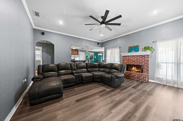 living room featuring a fireplace, wood-type flooring, plenty of natural light, and ornamental molding