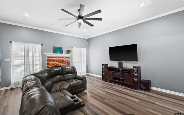 living room with ceiling fan, wood-type flooring, ornamental molding, and a brick fireplace