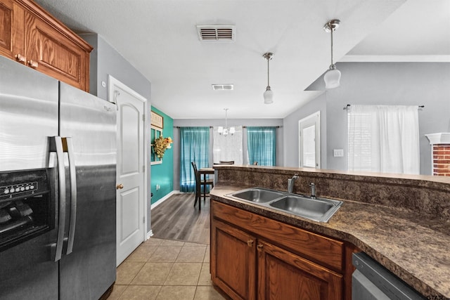 kitchen featuring stainless steel appliances, sink, pendant lighting, light hardwood / wood-style flooring, and a notable chandelier