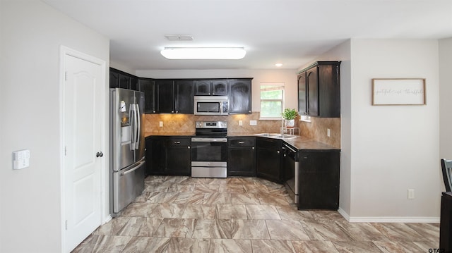 kitchen with decorative backsplash, visible vents, a sink, dark cabinetry, and stainless steel appliances