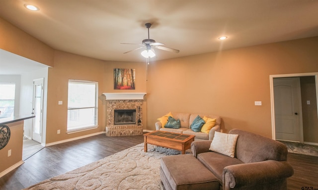 living area with a fireplace with raised hearth, a ceiling fan, baseboards, recessed lighting, and wood finished floors