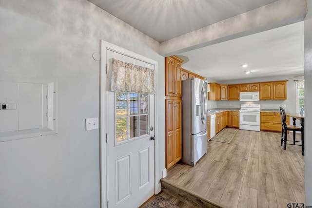 kitchen featuring light wood-type flooring, electric panel, and white appliances