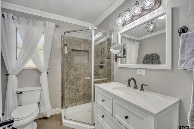 bathroom featuring a shower with door, ornamental molding, vanity, and toilet