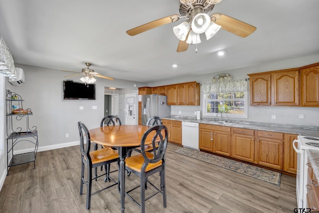 dining room with ceiling fan, a wall mounted air conditioner, sink, and light hardwood / wood-style flooring