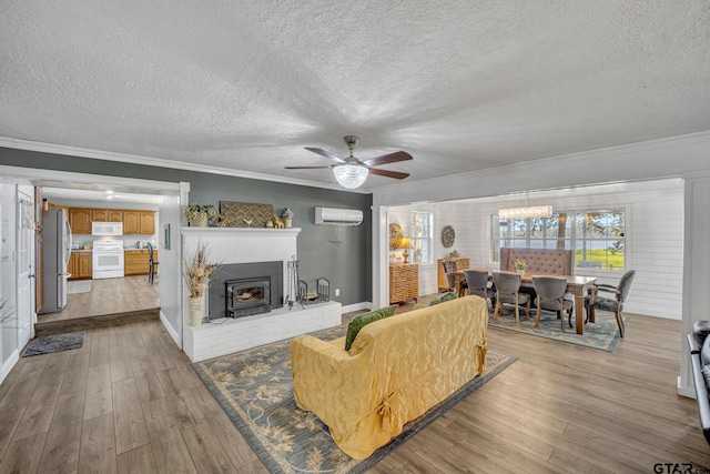 living room featuring crown molding, a wall mounted AC, light hardwood / wood-style floors, and a textured ceiling