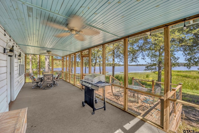 unfurnished sunroom with ceiling fan and a water view