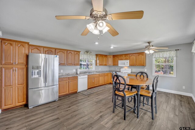 kitchen with light stone counters, white appliances, sink, and hardwood / wood-style floors