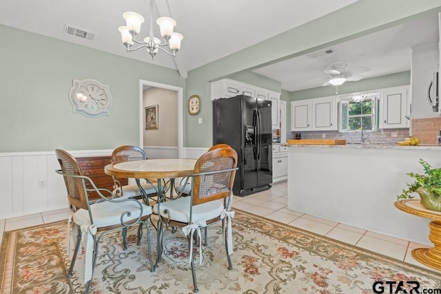 tiled dining area featuring ceiling fan with notable chandelier