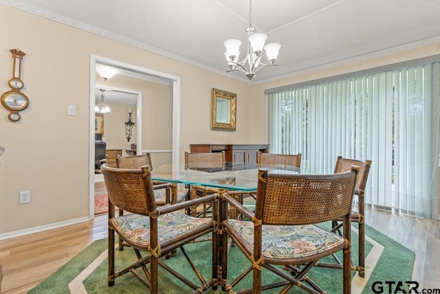 dining space with a notable chandelier, ornamental molding, and light hardwood / wood-style flooring