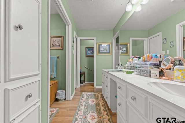 bathroom with vanity, wood-type flooring, and a textured ceiling