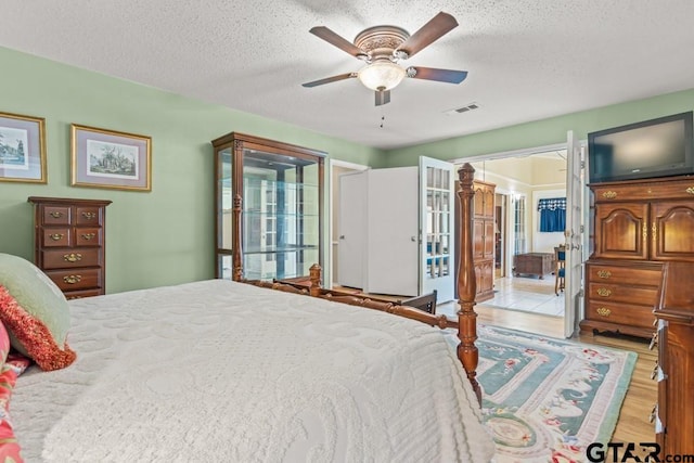 bedroom with a textured ceiling, light hardwood / wood-style flooring, and ceiling fan