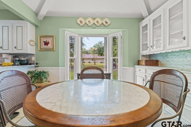 dining space with beam ceiling and light tile patterned floors