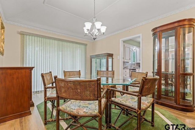 dining area featuring ornamental molding, light wood-type flooring, and a notable chandelier