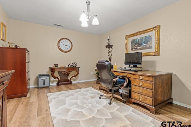 home office with a chandelier and light hardwood / wood-style flooring