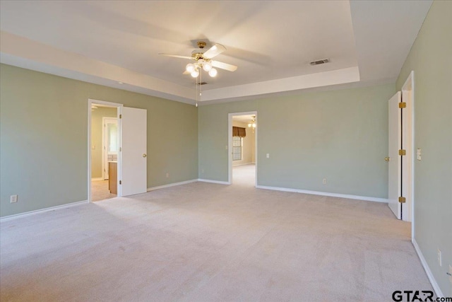 carpeted empty room with a tray ceiling and ceiling fan