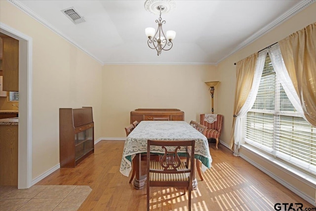 dining area featuring a chandelier, light wood-type flooring, and crown molding