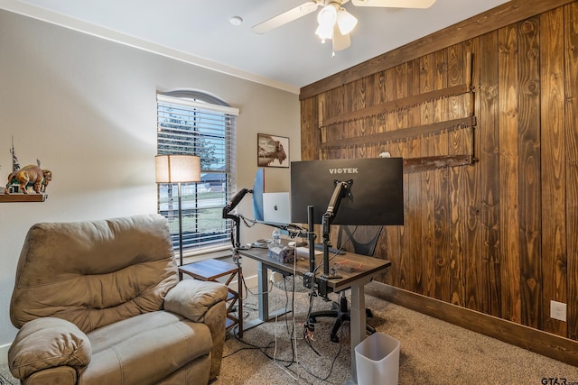 carpeted home office with crown molding, ceiling fan, and wood walls