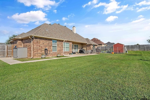 back of property featuring a lawn, a patio area, and a storage shed