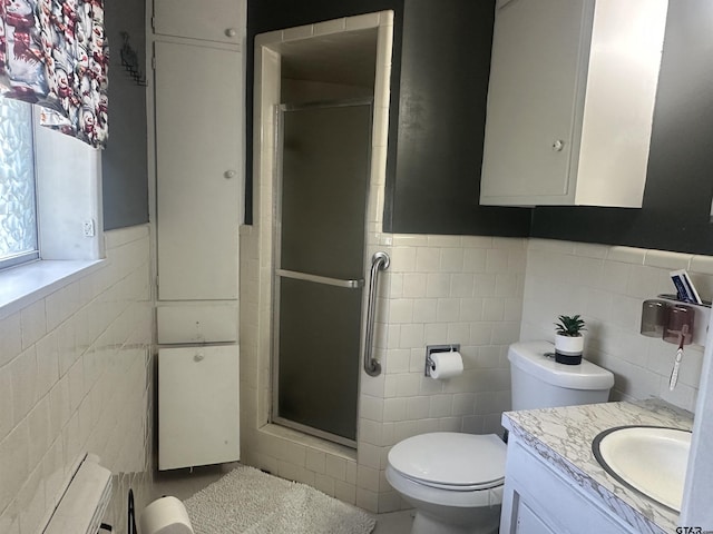 bathroom featuring vanity, toilet, a wainscoted wall, tile walls, and a stall shower