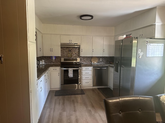 kitchen with stainless steel appliances, dark countertops, white cabinetry, and wood finished floors