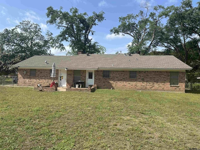 rear view of property featuring a lawn and brick siding