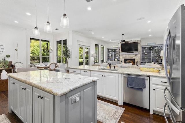 kitchen with a center island, hanging light fixtures, ceiling fan, appliances with stainless steel finishes, and white cabinetry