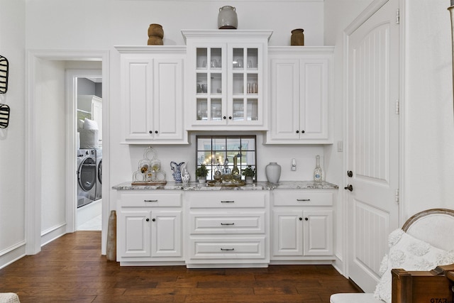 bar with white cabinets, washer and clothes dryer, light stone countertops, and dark wood-type flooring