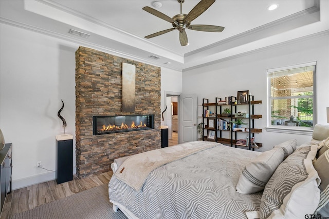185 Vz County Road 2103, Canton, TX 75103 - bedroom with a tray ceiling, light wood-type flooring, ornamental molding, a stone fireplace, and ceiling fan