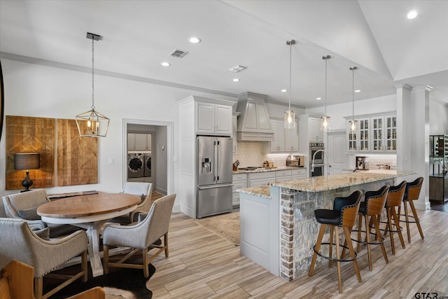 185 Vz County Road 2103, Canton, TX 75103 - kitchen featuring stainless steel appliances, premium range hood, separate washer and dryer, a kitchen bar, and light stone countertops