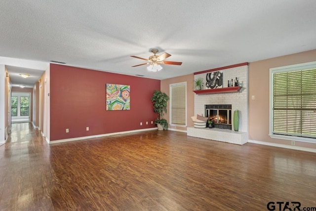 1656 Pineview Ln, Hideaway, TX 75771 - unfurnished living room featuring ceiling fan, wood finished floors, a brick fireplace, and a textured ceiling