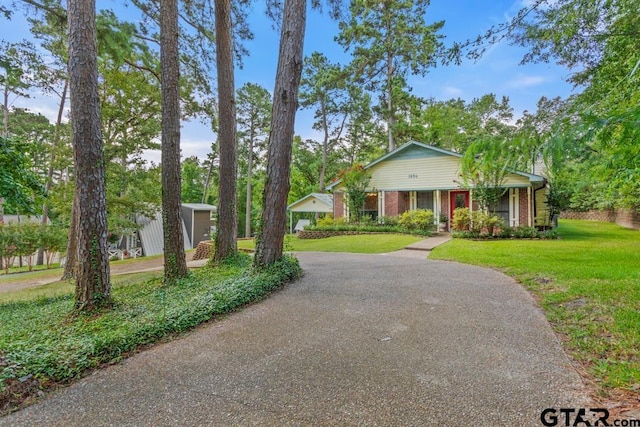 1656 Pineview Ln, Hideaway, TX 75771 - view of front of property featuring a front yard, brick siding, covered porch, and asphalt driveway