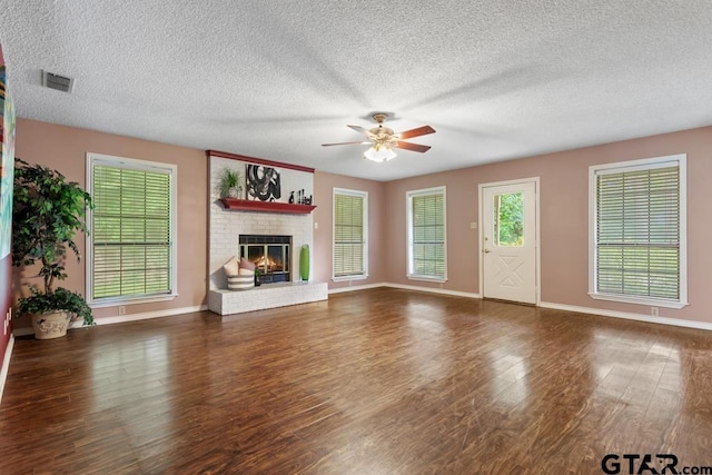 1656 Pineview Ln, Hideaway, TX 75771 - unfurnished living room featuring ceiling fan, a textured ceiling, a brick fireplace, and wood finished floors