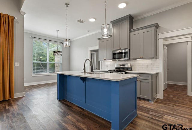 228 Smith Cir, Lindale, TX 75771 - kitchen featuring gray cabinetry, appliances with stainless steel finishes, a center island with sink, crown molding, and decorative backsplash