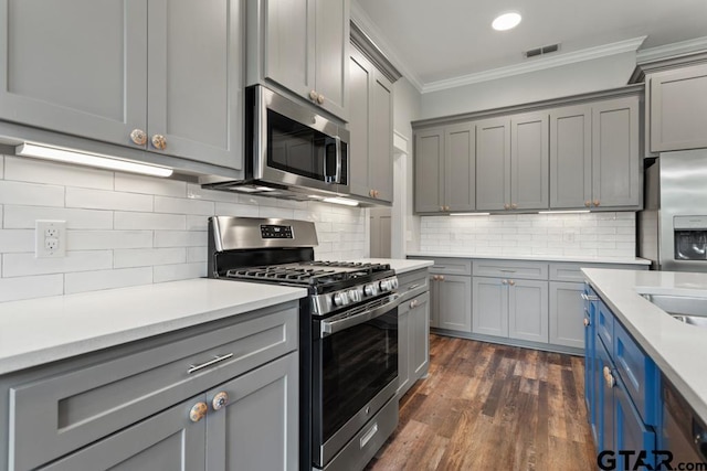 228 Smith Cir, Lindale, TX 75771 - kitchen with stainless steel appliances, gray cabinets, crown molding, light countertops, and dark wood-style flooring