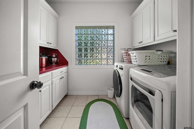 laundry room with baseboards, washing machine and dryer, light tile patterned flooring, and cabinet space