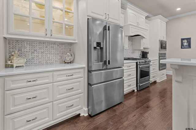 kitchen with tasteful backsplash, dark hardwood / wood-style floors, crown molding, white cabinets, and appliances with stainless steel finishes