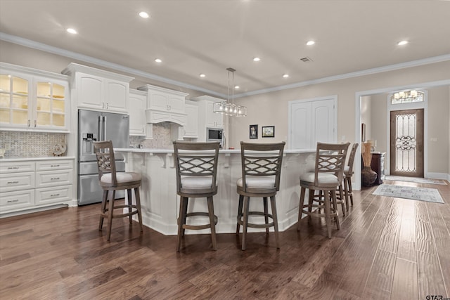 kitchen with white cabinets, appliances with stainless steel finishes, backsplash, and a spacious island