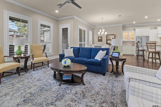 living room featuring dark hardwood / wood-style floors, ornamental molding, and ceiling fan with notable chandelier