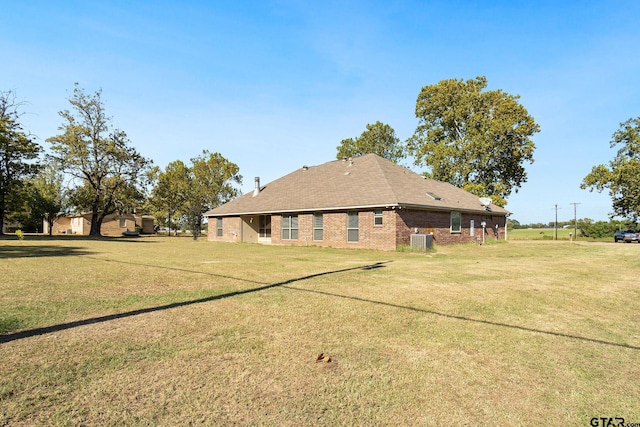 rear view of property featuring central AC and a yard