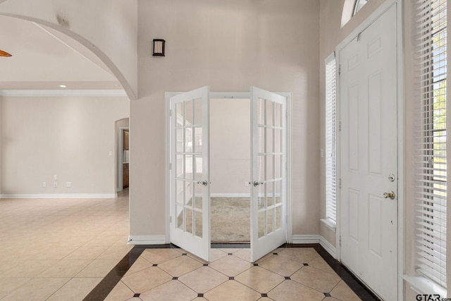 tiled entrance foyer with a towering ceiling, french doors, and crown molding