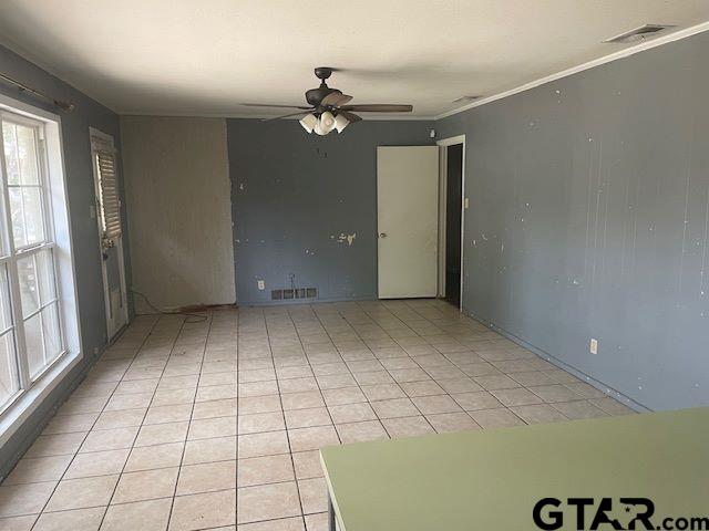 empty room featuring visible vents, ornamental molding, ceiling fan, and light tile patterned floors