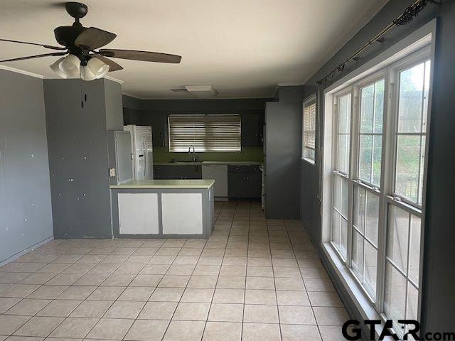 kitchen featuring a ceiling fan, a peninsula, white refrigerator with ice dispenser, a sink, and light tile patterned floors