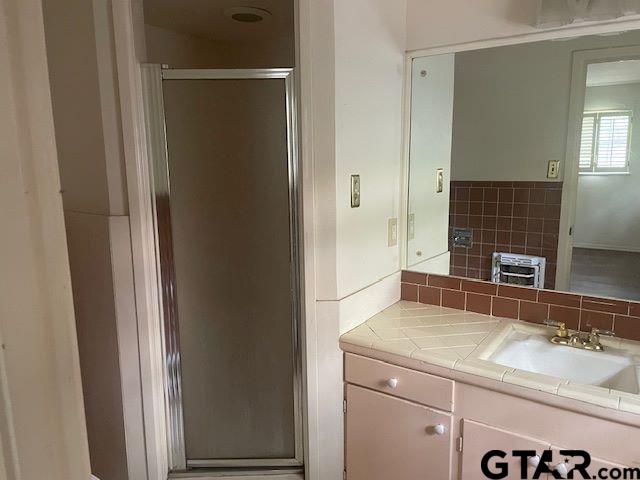 bathroom featuring vanity, tasteful backsplash, and a stall shower